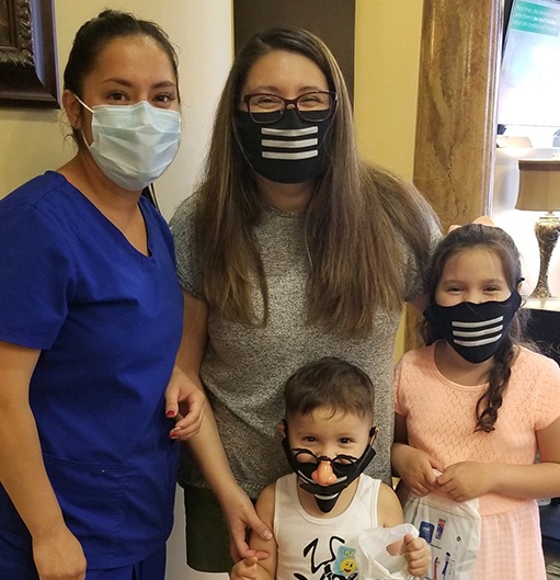 Dental team member and family of three wearing protective face masks