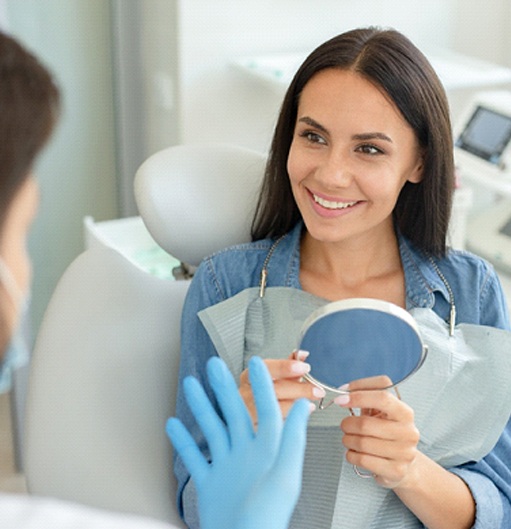 Smiling woman talking to dentist while holding dental mirror