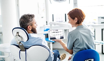 Smiling dental assistant and patient looking at X-ray