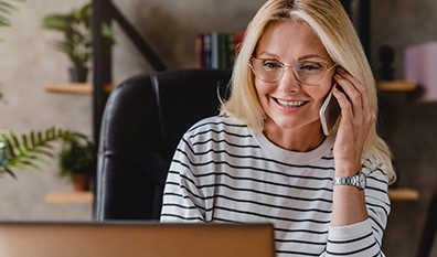 Woman with glasses smiling while talking on phone