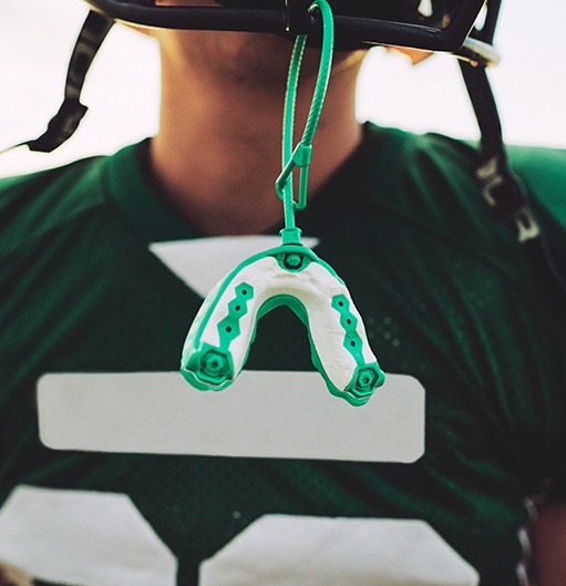 Child with an athletic mouthguard hanging from helmet