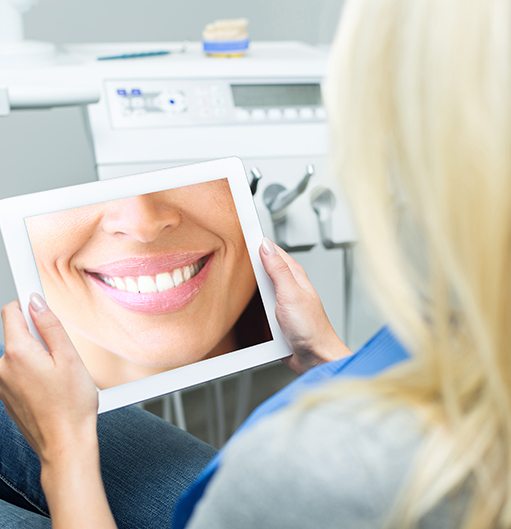Woman looking at digital imaging smile design on tablet computer
