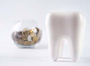 Model tooth standing in front of a bowl of coins