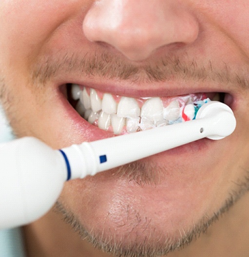 close-up of a man brushing his teeth with an electric toothbrush