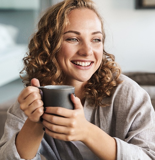 a person smiling and drinking a cup of coffee
