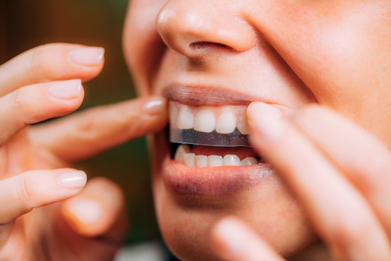A woman using a teeth whitening strip